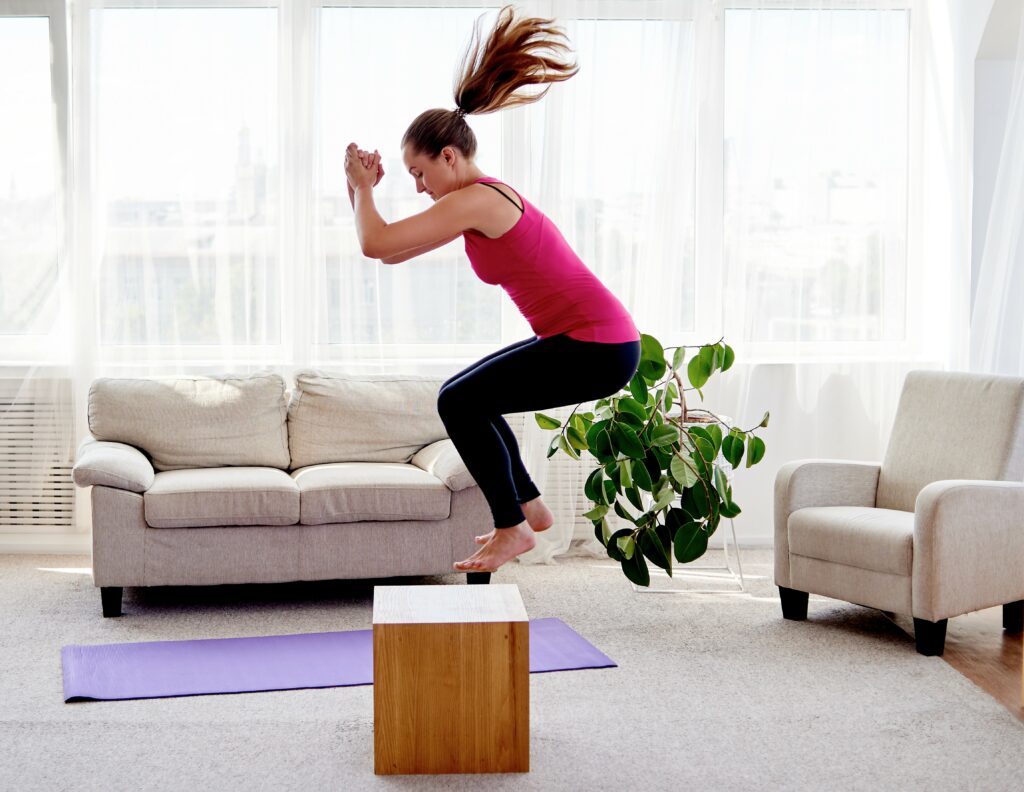 Kvinne hopper opp på boks i en treningsøkt